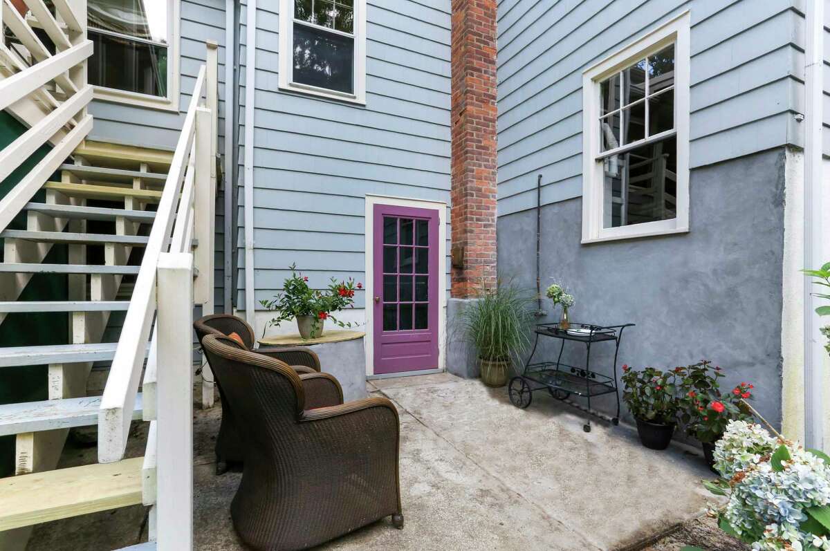 From the covered porch there are stairs down to a diminutive patio and the backyard. The house is hidden from view of passing motorists, sitting behind a scrim of mature trees, and the entire property is bordered by woodlands that create a cocoon of privacy.