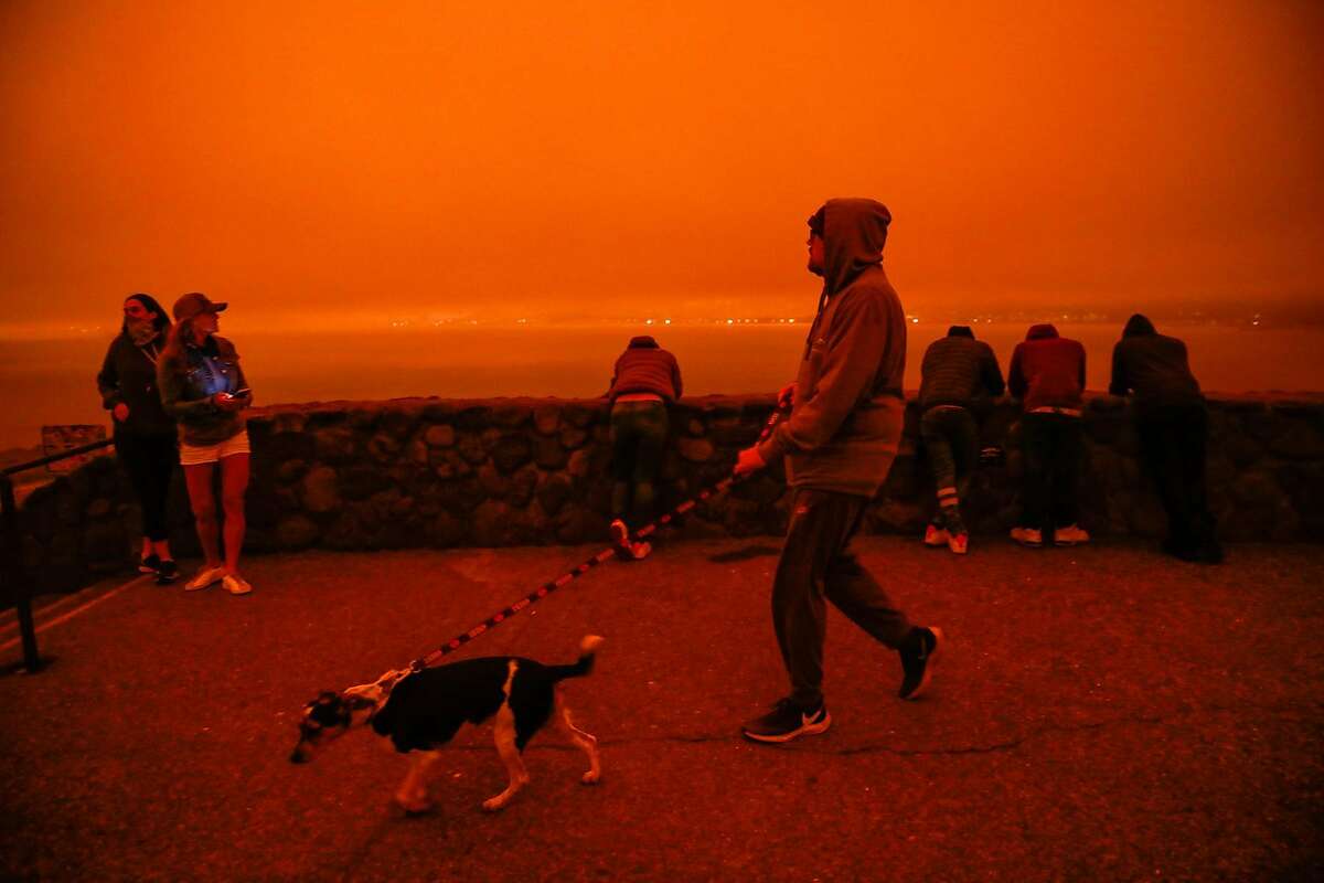 People hang out at an overlook at Golden Gate Bridge which was shrouded in dark orange smoke in Saulsalito, Calif. Wednesday, September 9, 2020 due to multiple wildfires burning across California and Oregon.