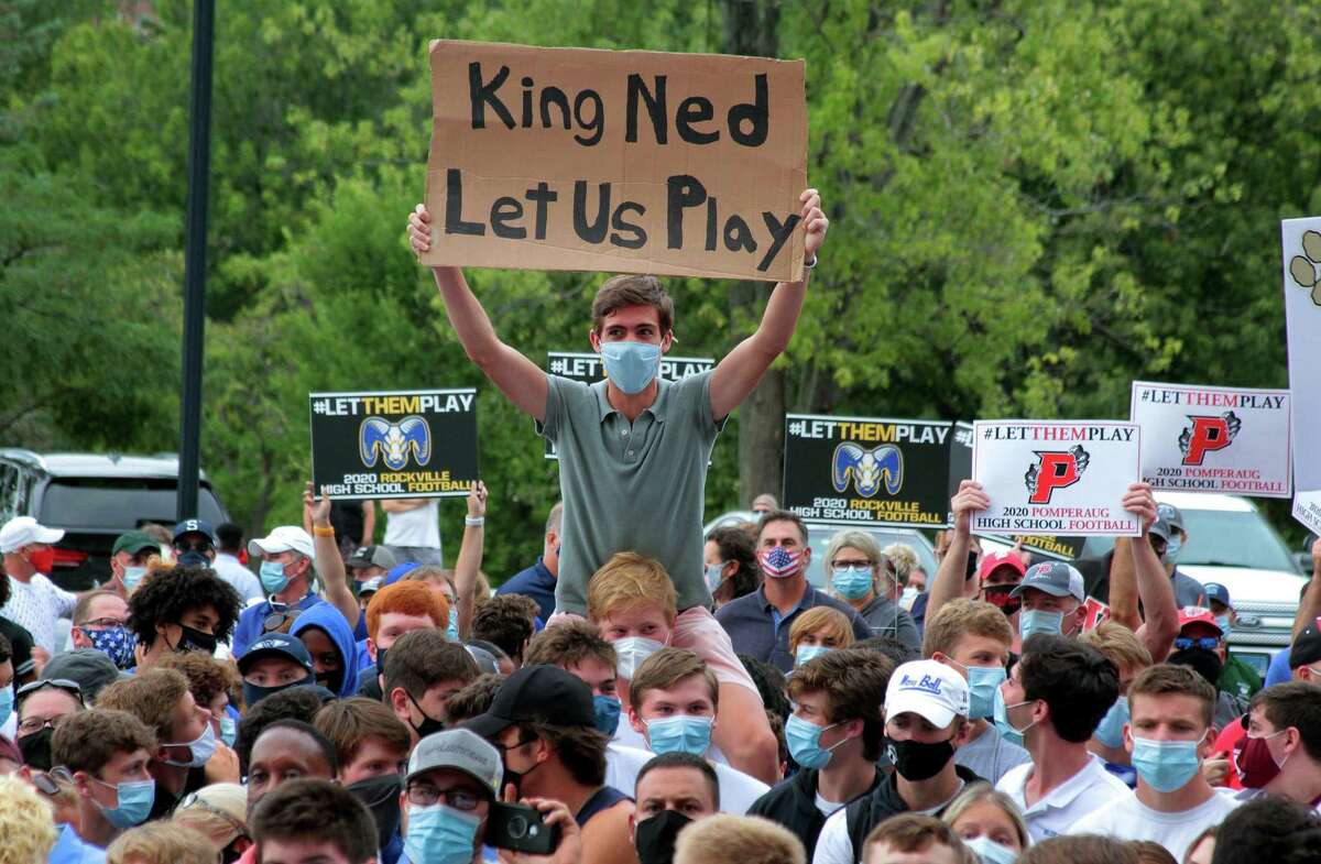 A youth holds a sign that reads, "King Ned Let Us Play" during a rally held on the grounds of the State Capitol building in Hartford, Conn., on Wednesday Sept. 9, 2020. High school football coaches and players from across the state came to Hartford to protest not being able to play in the upcoming season due to the coronavirus.
