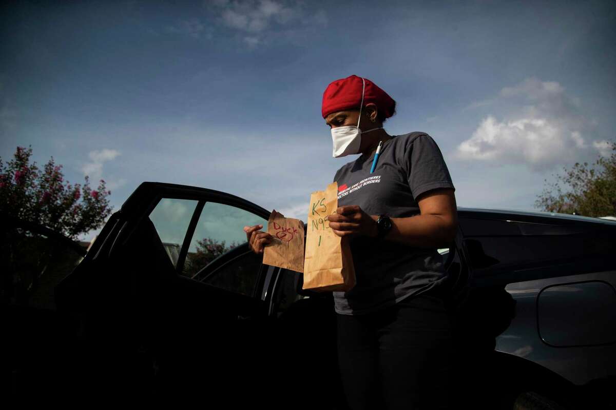 Kira Smith of the group Doctors Without Borders holds paper bags containing N95 masks on Wednesday, Sept. 9, 2020, in Jersey Village before entering a nursing home.