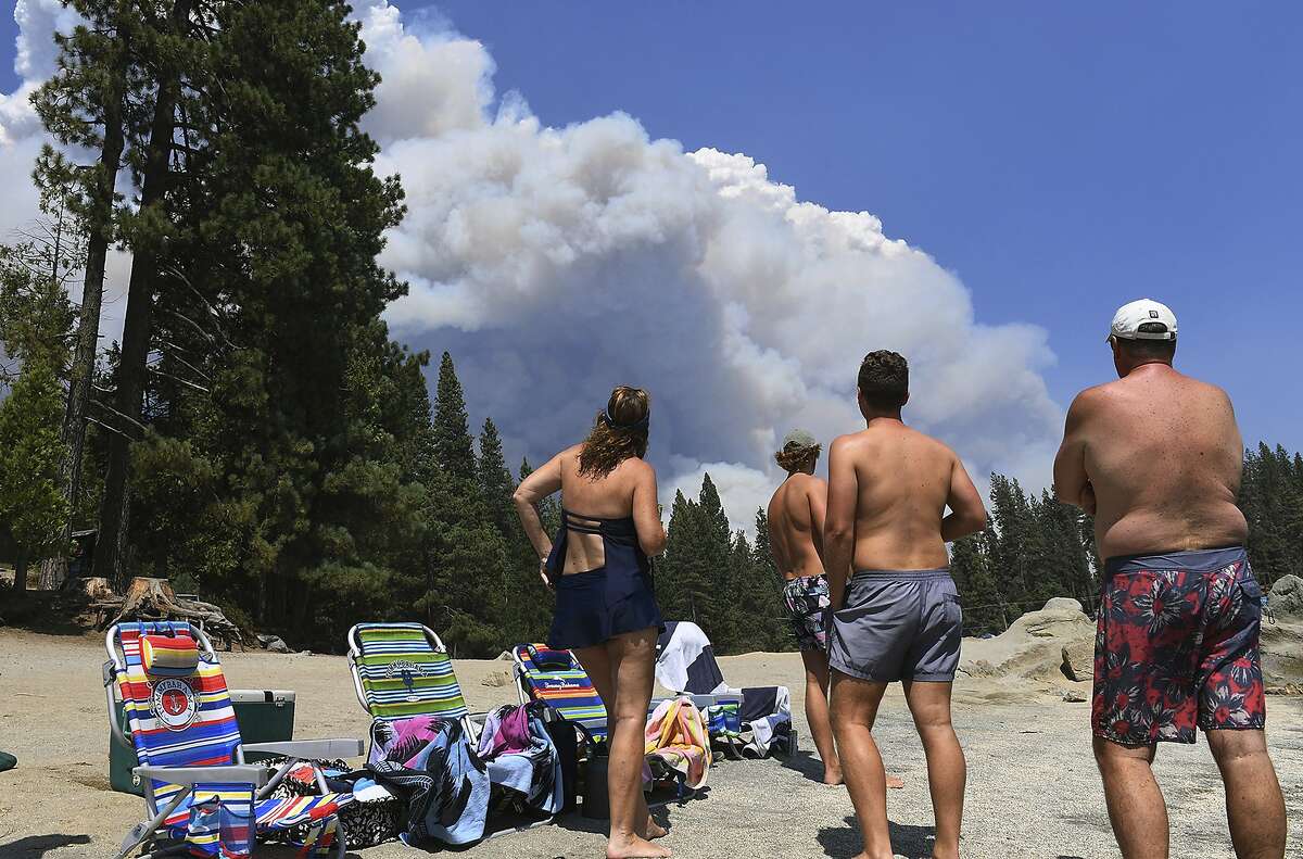 A family from Ventura County watches, from the shore of Shaver Lake, the billowing smoke from the Creek Fire, Saturday, Sept. 5, 2020, northeast of Fresno, Calif. (Eric Paul Zamora/The Fresno Bee via AP)