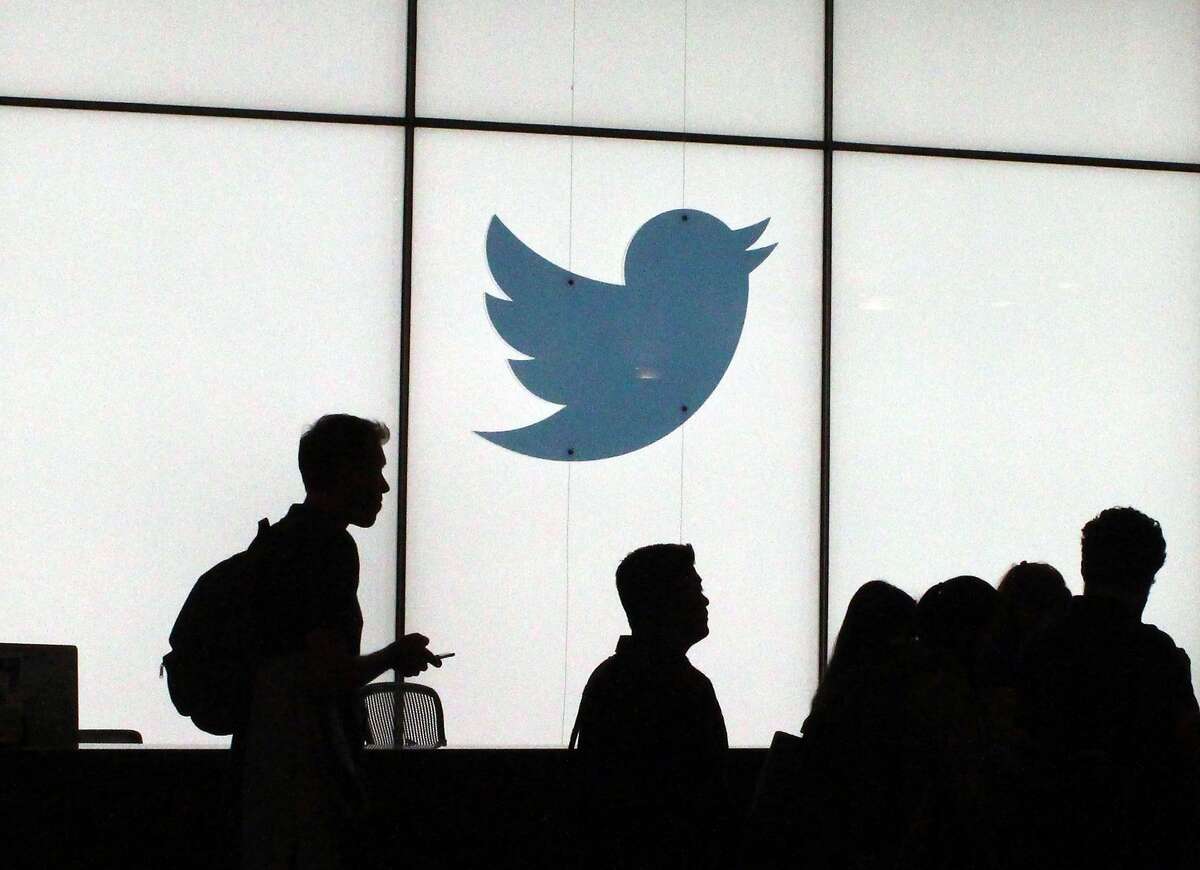 In this file photo taken on August 13, 2019, employees walk past a lighted Twitter logo as they leave the company's headquarters in San Francisco.