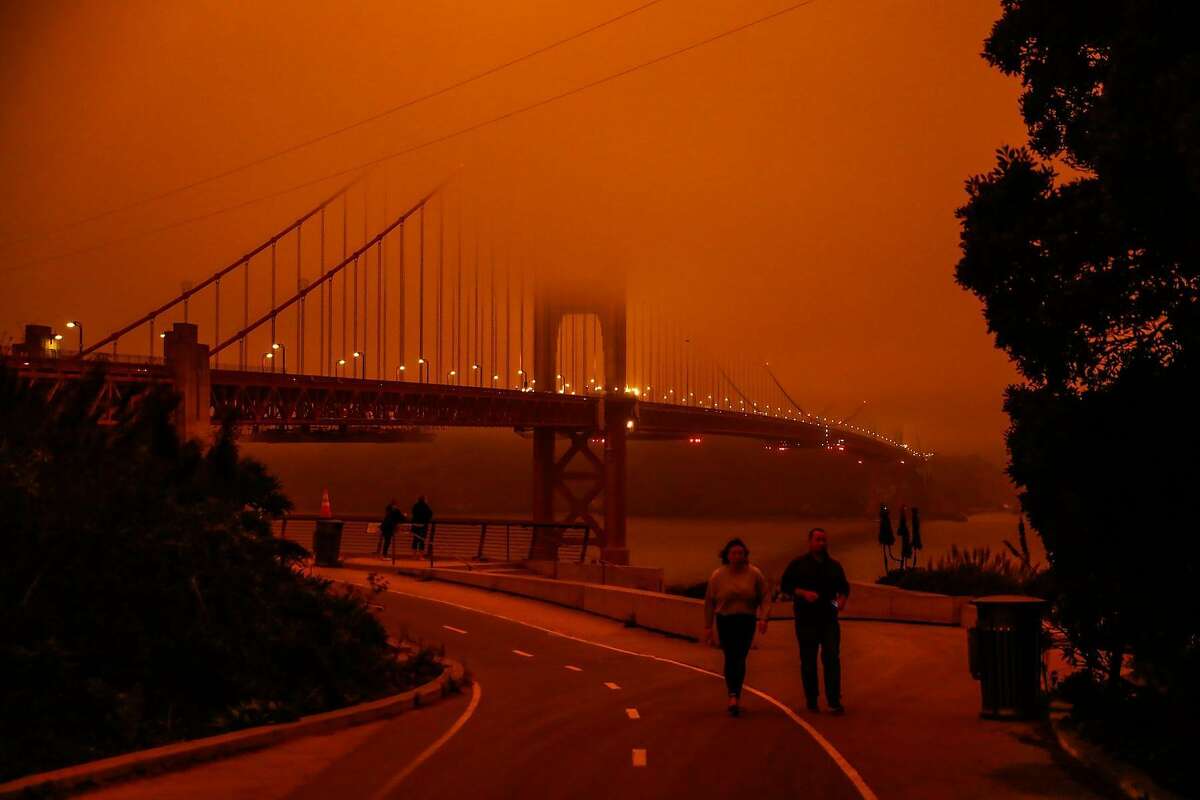 People check out the Golden Gate Bridge which was shrouded in dark orange smoke in San Francisco, Calif. Wednesday, September 9, 2020 due to multiple wildfires burning across California and Oregon.