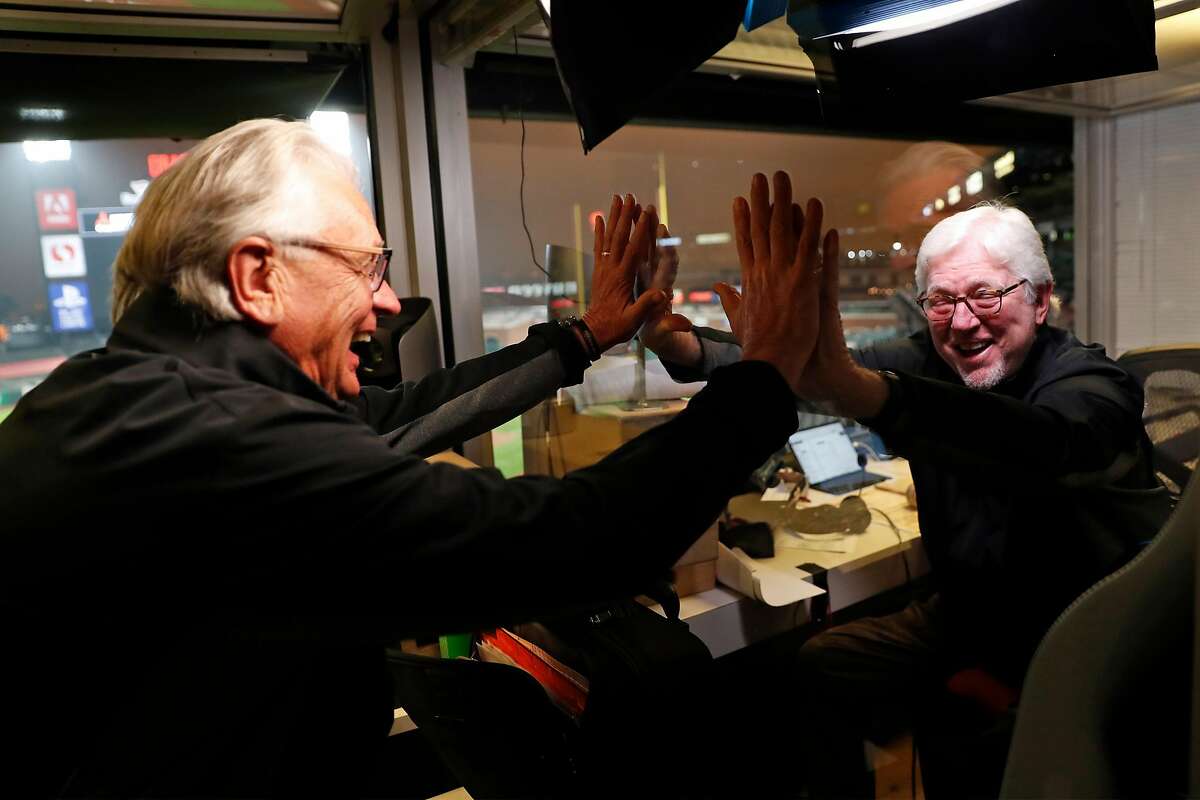 Duane Kuiper (left) and longtime broadcast partner Mike Krukow high-five through Plexiglass before a game at Oracle Park in September.