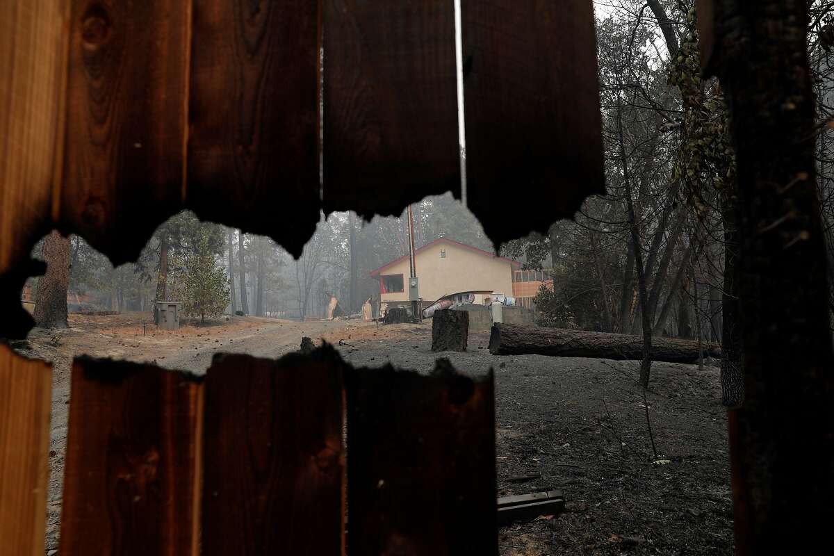 A home under renovation and largely untouched by flames, is seen through its burned fence adn escaped devastation from the North Complex fire in Berry Creek, Calif., on Saturday, September 12, 2020.