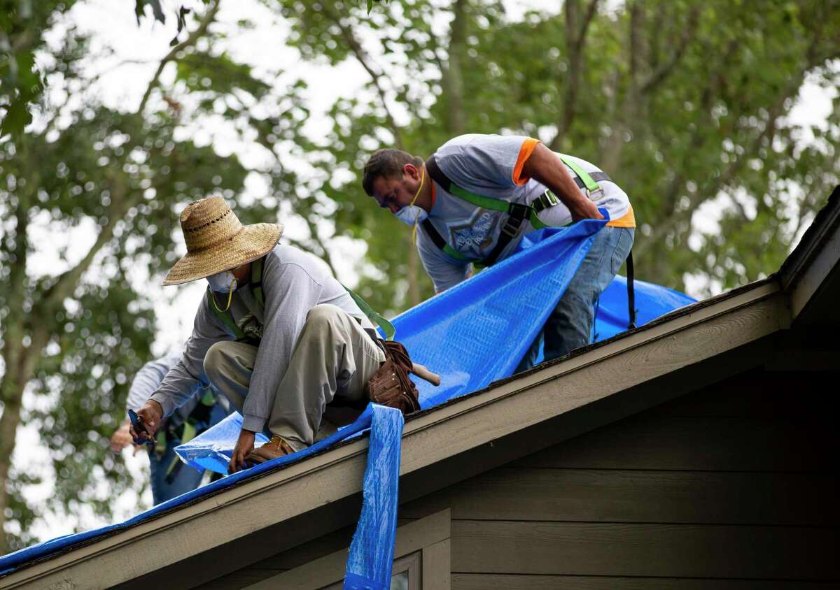 Roofing tradesmen from Texas Engineered Roofing and General Contracting remove a protective roofing tarp on a home near Lake Conroe, Friday, Sept. 11, 2020. The company lead a not-for-profit community relations project in the Walden community after they heard of a community member receiving a botched job from a previous contractor.