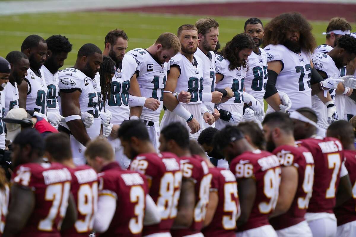 Members of the Washington Football Team and Philadelphia Eagles lock arms as they join in the middle of the field to form an oval before the start of an NFL football game, Sunday, Sept. 13, 2020, in Landover, Md. (AP Photo/Alex Brandon)