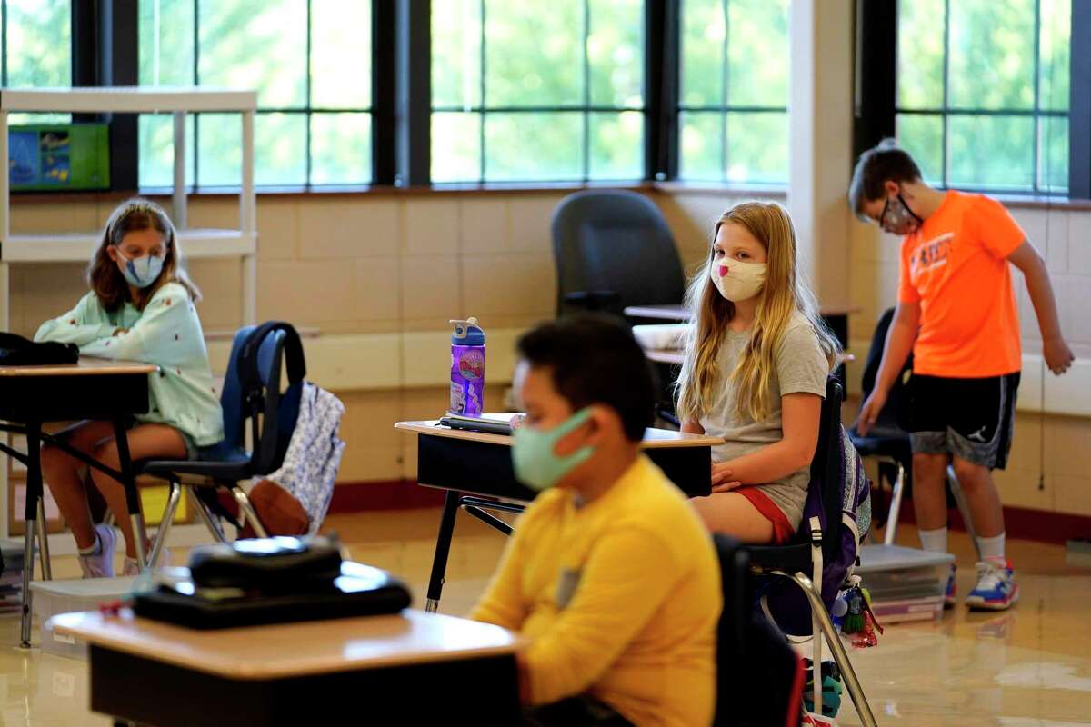 Estudiantes de quinto grado portan mascarillas en espera de su maestro en el aula en la Escuela Primaria Oak Terrace en Highwood, Illinois, parte del distrito escolar de North Shore.