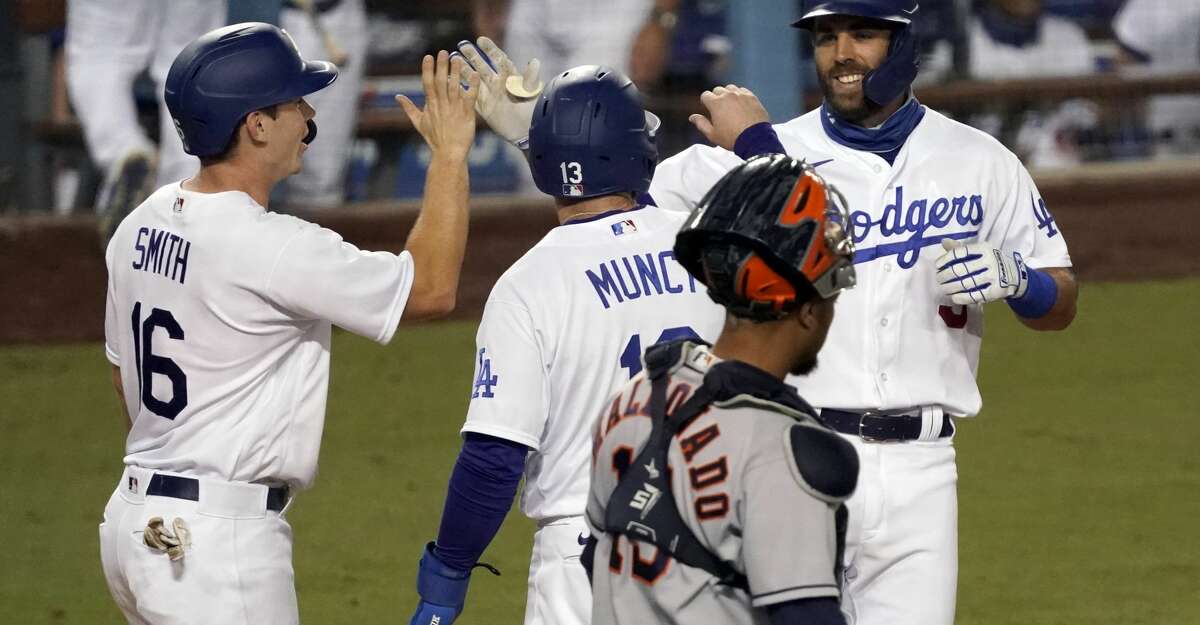 Los Angeles Dodgers' Chris Taylor, right, gets congratulations from Will Smith, left, and Max Muncy after hitting a three-run home run, with Houston Astros catcher Martin Maldonado, foreground, watching, during the eighth inning of a baseball game in Los Angeles, Sunday, Sept. 13, 2020. (AP Photo/Alex Gallardo)
