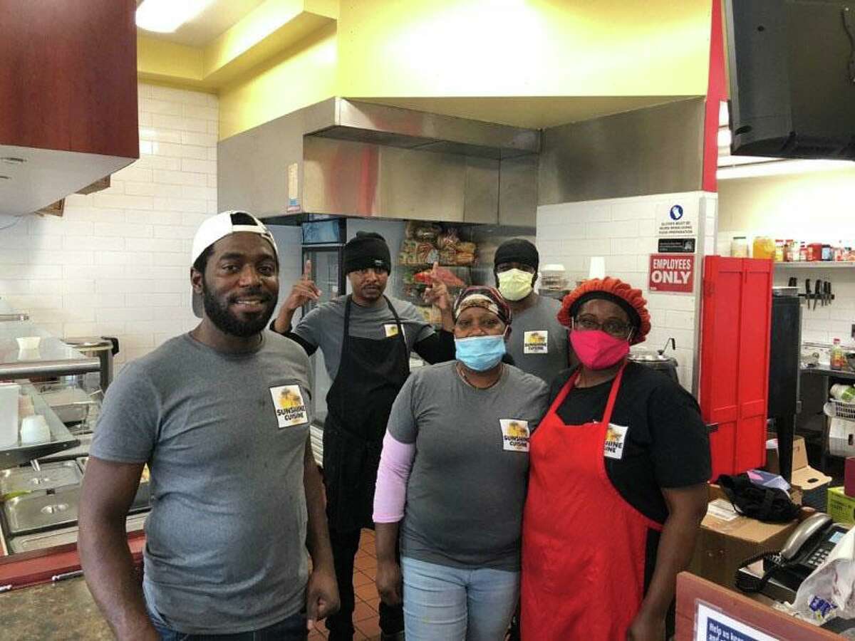 Foutin Reid, left, owner of Stamford’s Sunshine Cuisine, and his staff pause while preparing meals in the restaurant’s kitchen as part of a new partnership with the Catholic Charities of Fairfield County, which has seen need increase drastically at its food pantries in Stamford and Bridgeport since the start of the coronavirus pandemic.