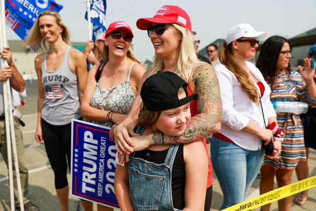 Tessa Jacques embraces daughter Caroline Jacques, 9, as they and other supporters of President Trump wait hoping to catch a glimpse of the President after he landed.