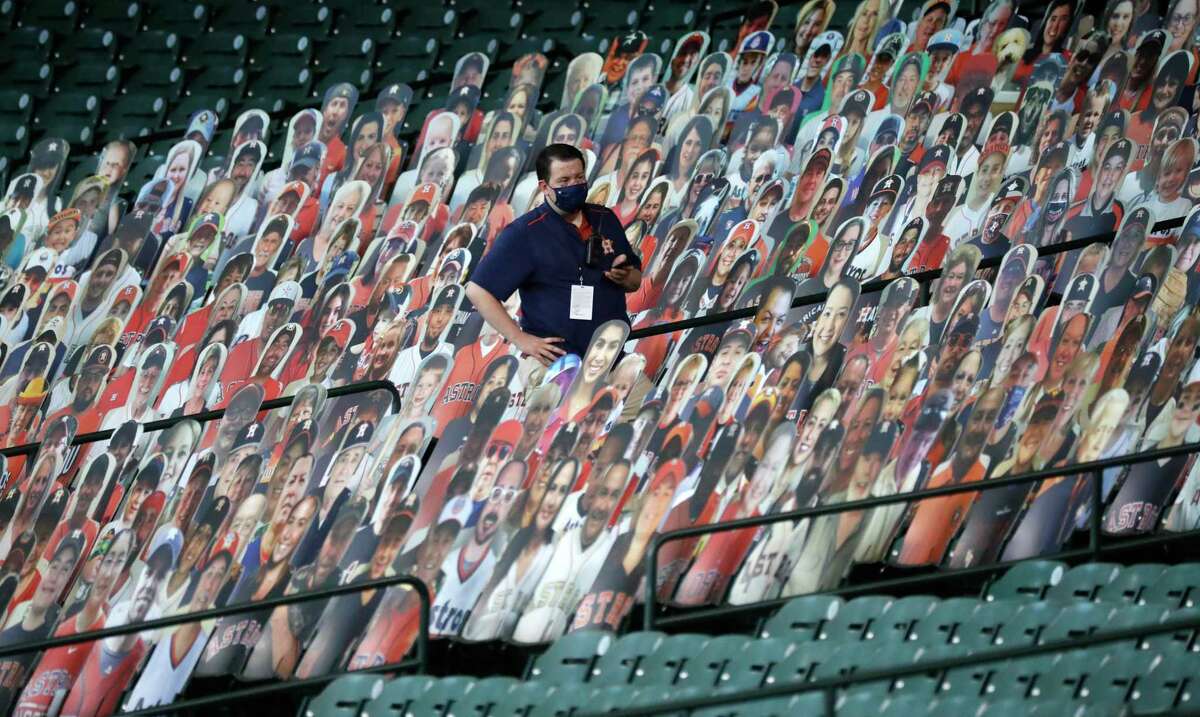 Brandon Puls, Houston Astros retail operations manager, looks for a foul ball among the fan cutouts in the stands during the third inning of an MLB baseball game at Minute Maid Park, Sunday, August 16, 2020, in Houston.