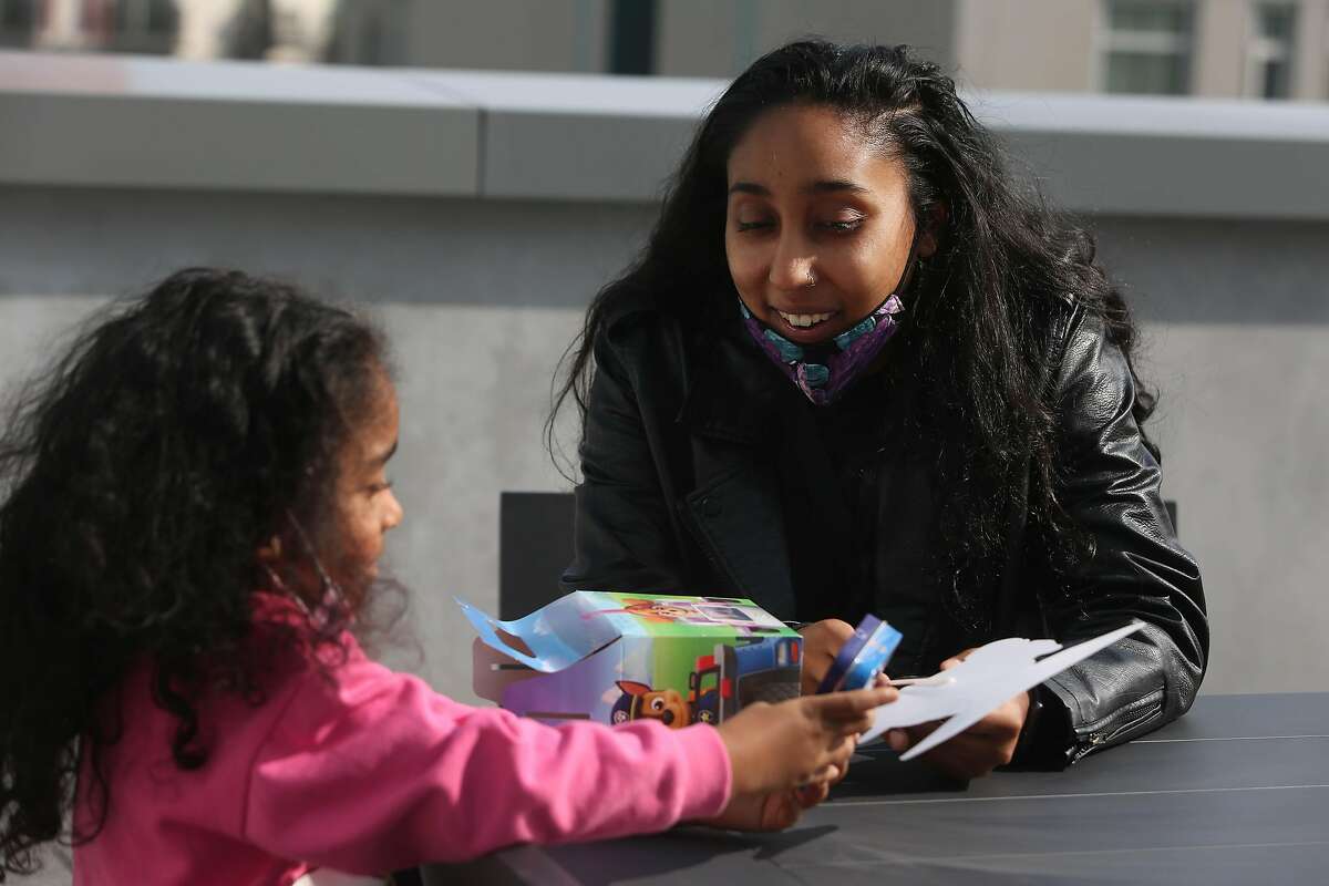 Maile Chand (right) , doula coordinator for Sister Web’s Mana Pasefika and community researcher for Abundant Birth Project, talks with her daughter Melilani Scott (left), 4, as Scott shows her mother the contents of a box from a classmate’s birthday celebration as they spend time together on a roof deck at their apartment building on Monday, September 14, 2020 in San Francisco, Calif.