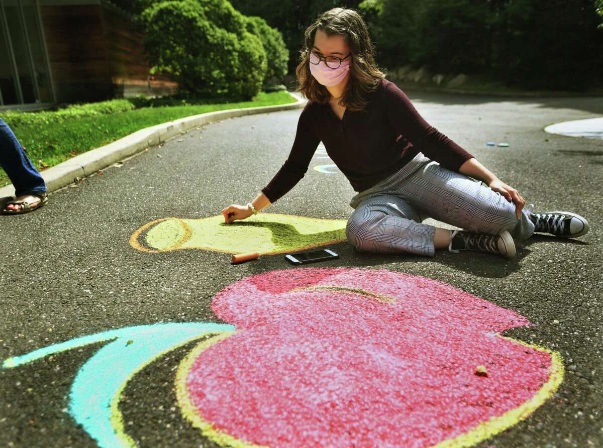 Ariel Langberg, 16, of Ridgefield, uses chalk to draw an apple and pot of honey, symbols of Rosh Hashana, outside the entrance of Temple B'Nai Chaim. The chalk drawing was the inaugural event of the temple’s youth group, kicking off the High Holy Days.