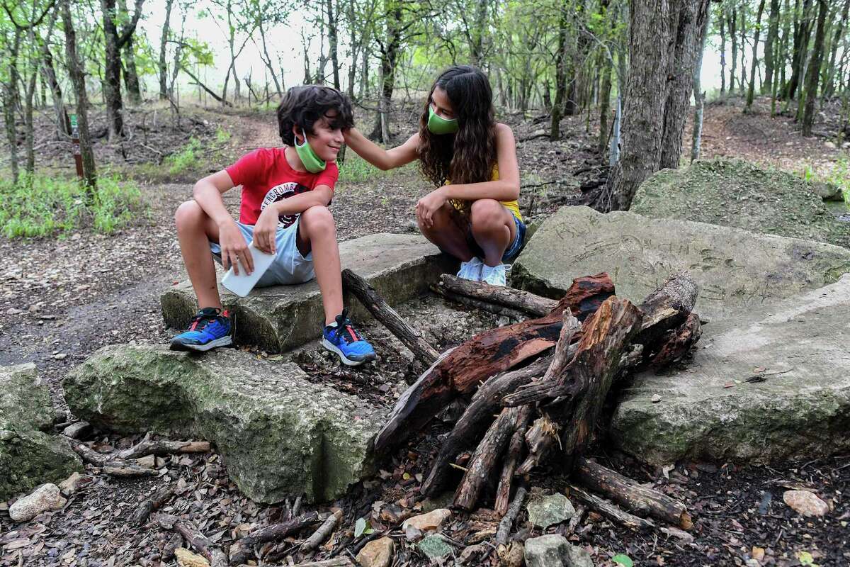 Elizabeth and William Gutierrez sit by the remains of a deer that they made from wood gathered at McAllister Park for a school project. Once complete, they placed it by a foot trail in the park, but it was destroyed.
