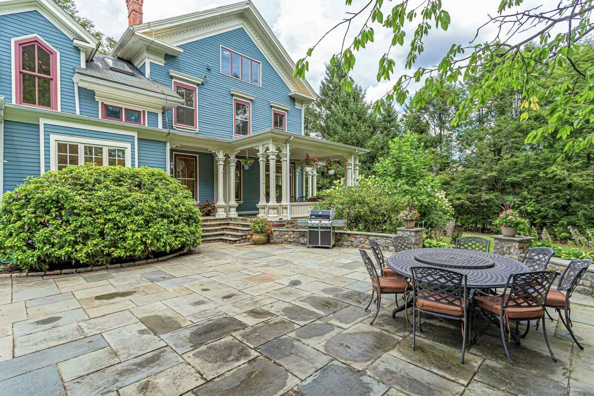 The backyard enjoys privacy, hidden behind mature trees, and yet this house is less than a mile from the Merritt Parkway. The historical society website contains an early photograph of this house, which then was white. The covered front porch, decorative columns, and French doors depicted in that photo are still intact, although the shutters on the front facade no longer exist. Few people use the front doors to enter the home anymore. More often than not they access this 12-room, 4,600-square-foot house from the wrap-around covered porch of the side entrance. To do so they must walk from the driveway with ample parking places, down a stone path and over two large granite grist wheels, perhaps from the farm that was once occupied this property.