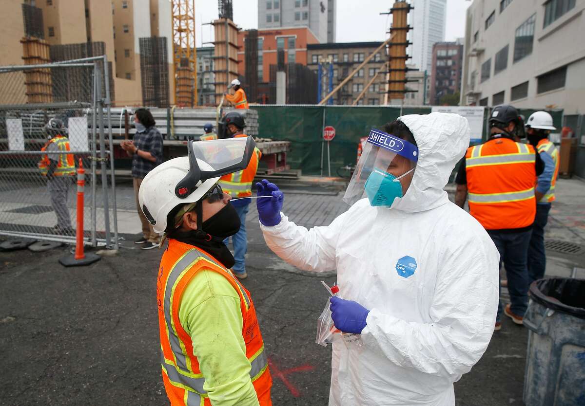 Armando Vidrio (right) collects a sample from a construction worker during weekly on-site coronavirus testing for Build Group employees and workers constructing a 302-unit residential building at 434 Minna Street in San Francisco, Calif. on Thursday, Sept. 3, 2020.