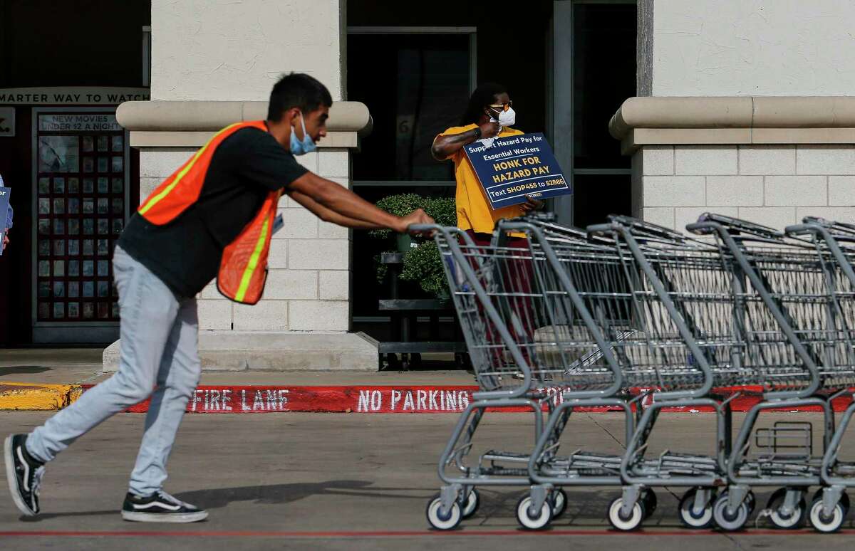 William Cox, center, with United Food and Commercial Workers International Union Local 455, holds up a sign outside a Kroger store during a rally Tuesday, Sept. 15, 2020, in Houston.