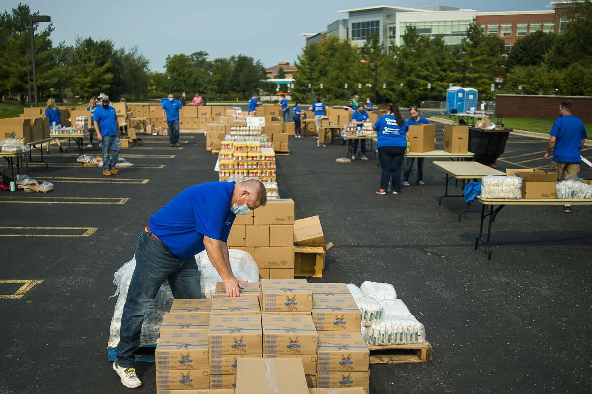Corteva Agrisciences employee Eric Krafft picks up a box of food as over 100 volunteers work to pack more than 40,000 pounds of food into boxes for residents of Midland County Wednesday, Sept. 16, 2020 at Dow Diamond. The event was organized through a partnership between Corteva, United Way of Midland County and the Great Lakes Loons. (Katy Kildee/kkildee@mdn.net)