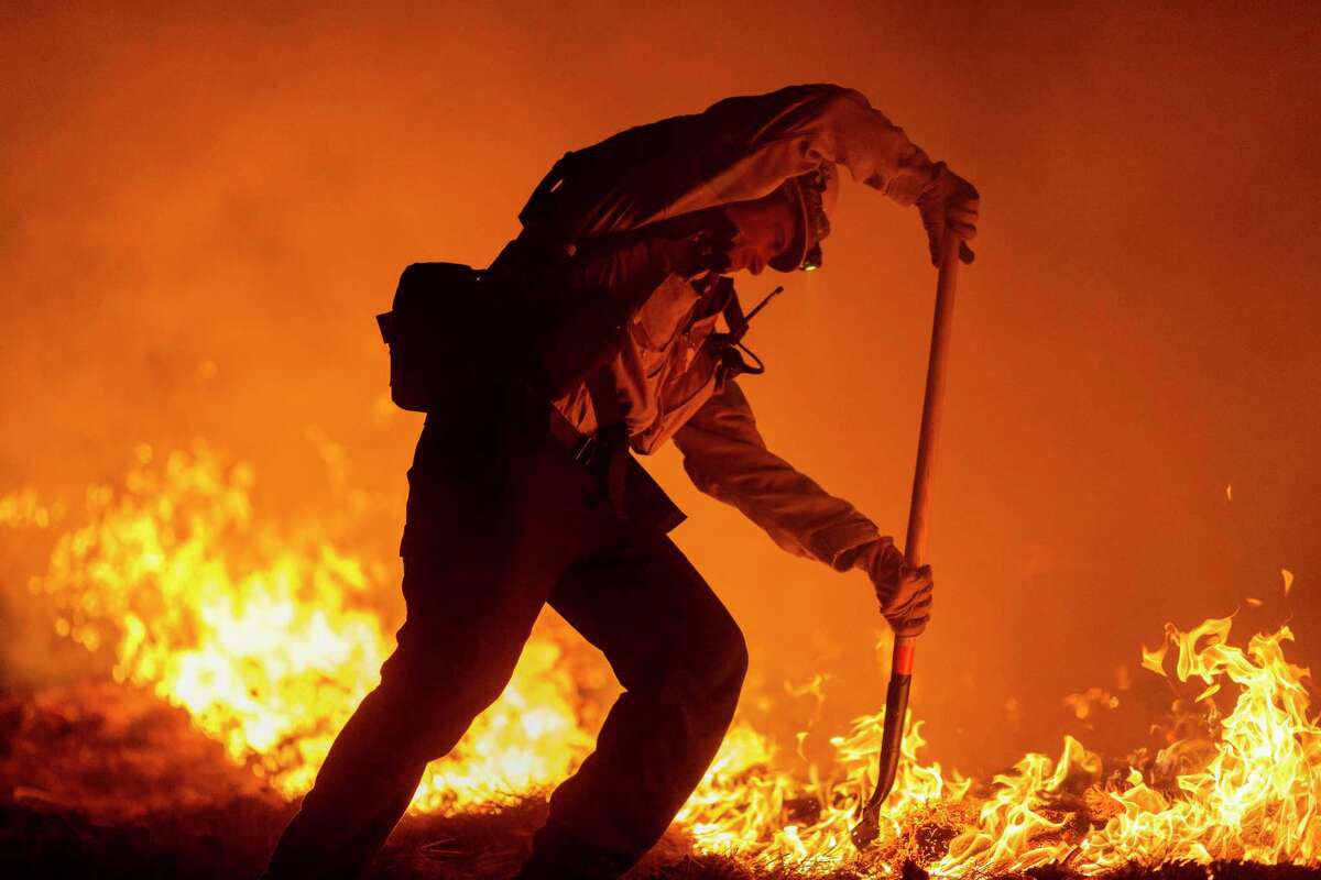 A firefighter struggles last week against the Bobcat Fire in Angeles National Forest. On the right and left, wildfires have been politicized.