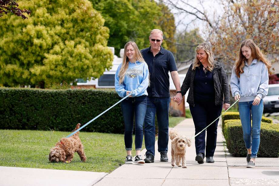 (Left-right) Daughter Sarah McKinney,18, who walks pet Toby, dad Rick McKinney, Rosemary Pathy-McKinney, and daughter Sabrina McKinney, 15, who walks pet Stanley,  go for an afternoon walk in their neighborhood in San Jose,California on April 8, 2020.  Rosemary Pathy-McKinney, is a San Jose schoolteacher who was on her way into brains surgery for a tumor at UCSF Parnassus on March 15 when the surgery was abruptly postponed because it was deemed "elective." The surgery ward was being prepared to only treat COVID patients who have still not materialized. Photo: Josie Lepe / Special To The Chronicle