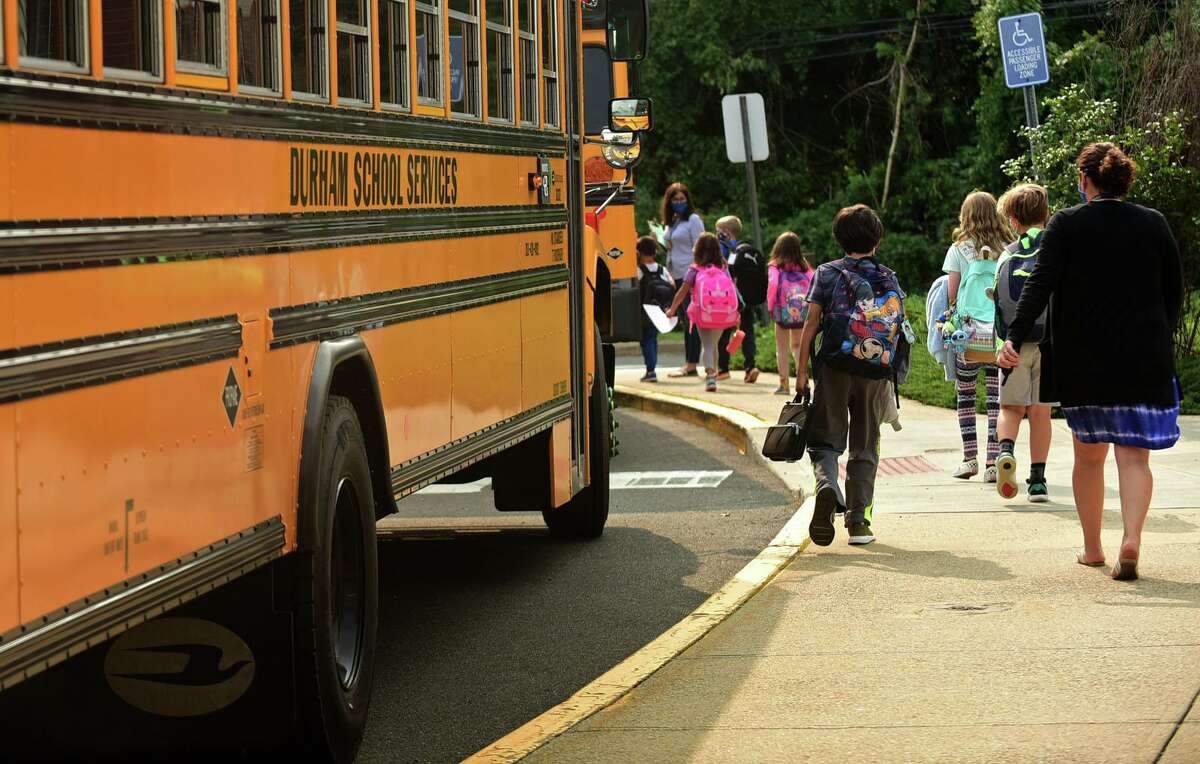 School staff help students boarding buses at Fox Run Elementary School Thursday, September 16, 2020. Norwalk Public Schools is working out the kinks in their bussing after adding bus monitors to help enforce COVID guidelines. To do this, the district is keeping on their seasonal help in the Transportation Department until October.