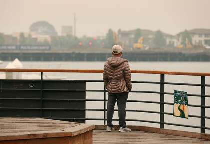 The Alameda shoreline is barely visible across the Oakland Estuary for a man standing at Jack London Square in Oakland on Sept. 10.
