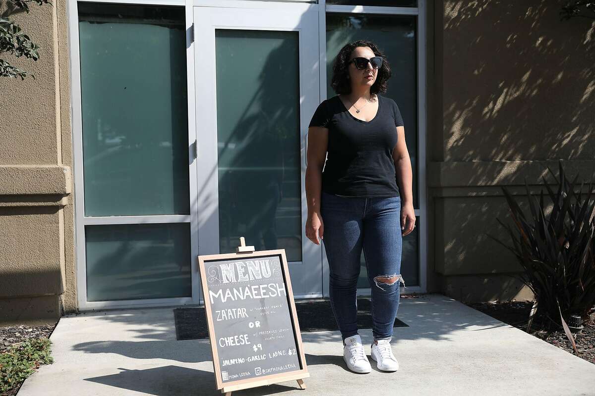 Mona Leena Michael of Oakland stands with the menu board she used at her pop up as she stands for a portrait outside the Bakery Lofts on Wednesday, September 16, 2020 in Oakland Calif. Michael, who is a chef, was selling flatbreads and other foods in front of her live/ work space at a pop up in Oakland before the health department shut her down for lack of a permit.