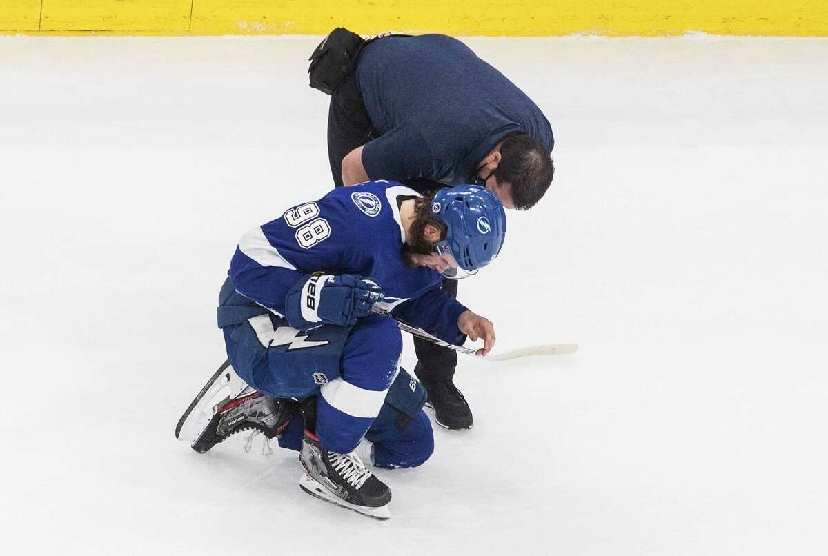 A trainer talks with Tampa Bay Lightning defenseman Mikhail Sergachev (98) after he was injured by a high stick during the third period against the New York Islanders in Game 5 of the NHL hockey Eastern Conference final, Tuesday, Sept. 15, 2020, in Edmonton, Alberta. (Jason Franson/The Canadian Press via AP)