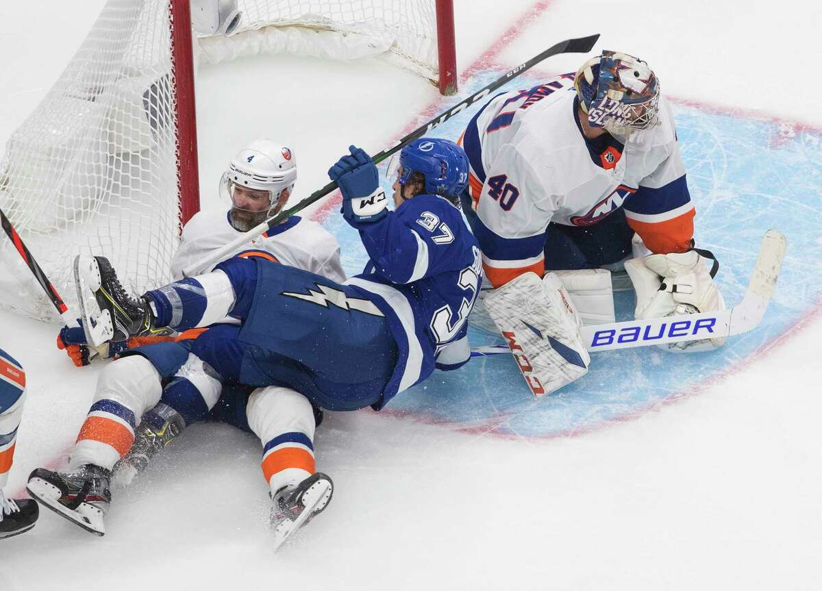 Tampa Bay Lightning left wing Yanni Gourde (37) and New York Islanders defenseman Andy Greene (4) crash into the net as Islanders goaltender Semyon Varlamov (40) looks for the puck during the second overtime in Game 5 of the NHL hockey Eastern Conference final, Tuesday, Sept. 15, 2020, in Edmonton, Alberta. (Jason Franson/The Canadian Press via AP)