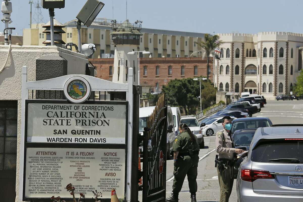 FILE - In this July 9, 2020, file photo, a correctional officer checks a car entering the main gate of San Quentin State Prison in San Quentin, Calif. California has launched a $30 million program to provide thousands of parolees with community services after they complete their prison sentences or are released months early because of the coronavirus pandemic, officials announced Thursday, Aug. 27, 2020. (AP Photo/Eric Risberg, File)
