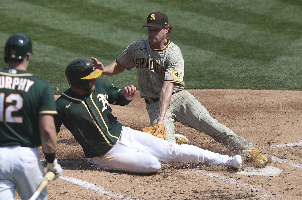 San Diego Padres' Garrett Richards tags out Oakland Athletics' Robbie Grossman on a strike out by Sean Murphy during the second inning of a baseball game in Oakland, Calif., Sunday, Sept. 6, 2020. (AP Photo/Jed Jacobsohn)