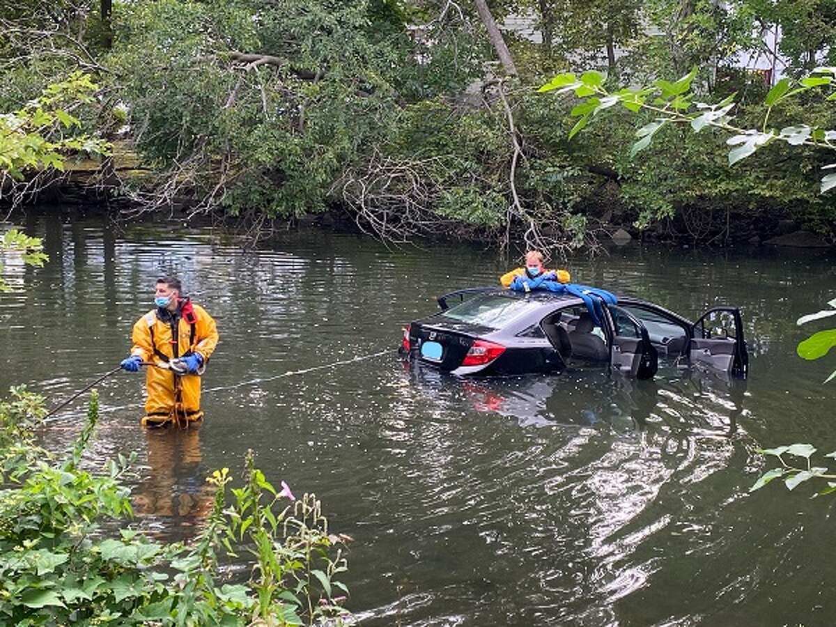 Stamford firefighters help rescue a woman who drove her car into the Rippowam River in downtown Stamford on Monday morning.