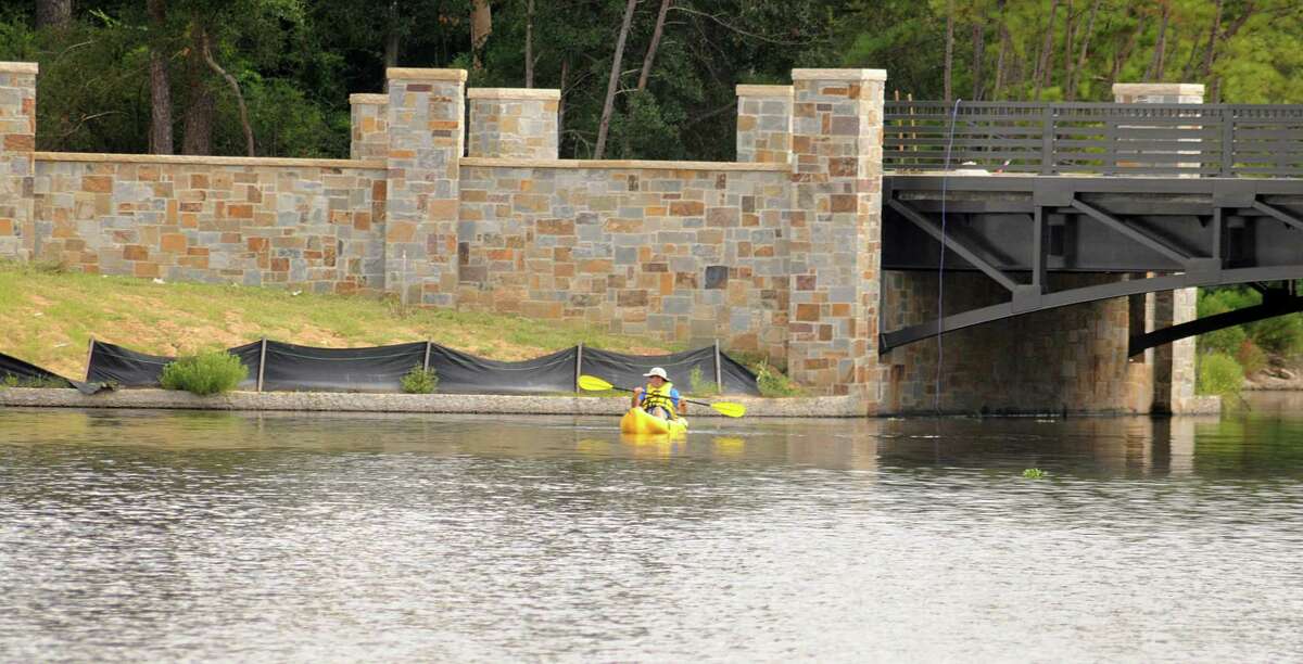 A kayaker on Lake Woodlands passes the new bridge that will connect Mitchell Island, on the east side of Lake Woodlands, located at Timberloch Place and Majestry Row.