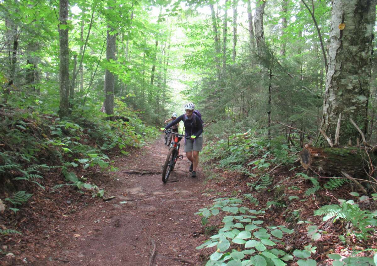 Outdoors writer Gillian Scott pushes her bike during a recent mountain bike outing near Inlet. (Herb Terns / Times Union)