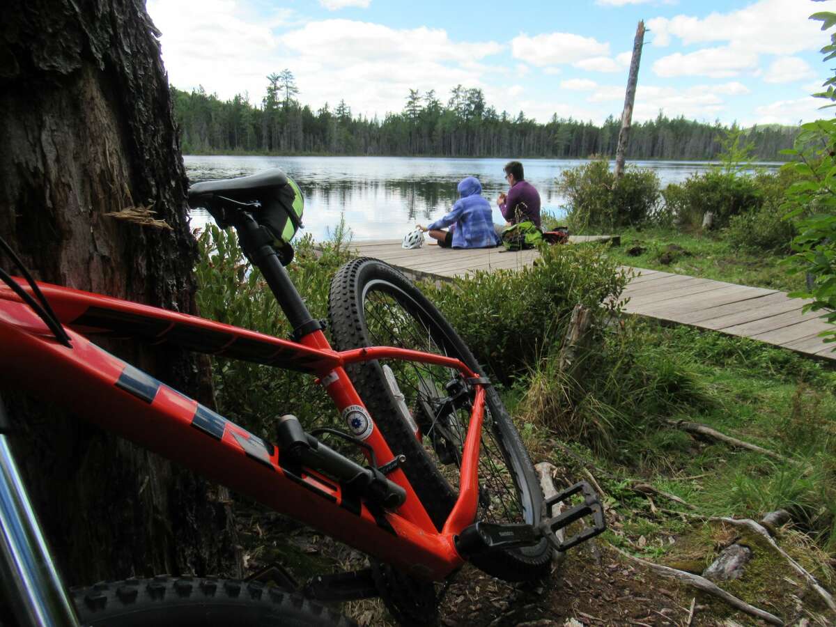 Outdoors writer Gillian Scott and her daughter relax lakeside after a mountain bike ride in the Moose River Plains area. (Herb Terns / Times Union)