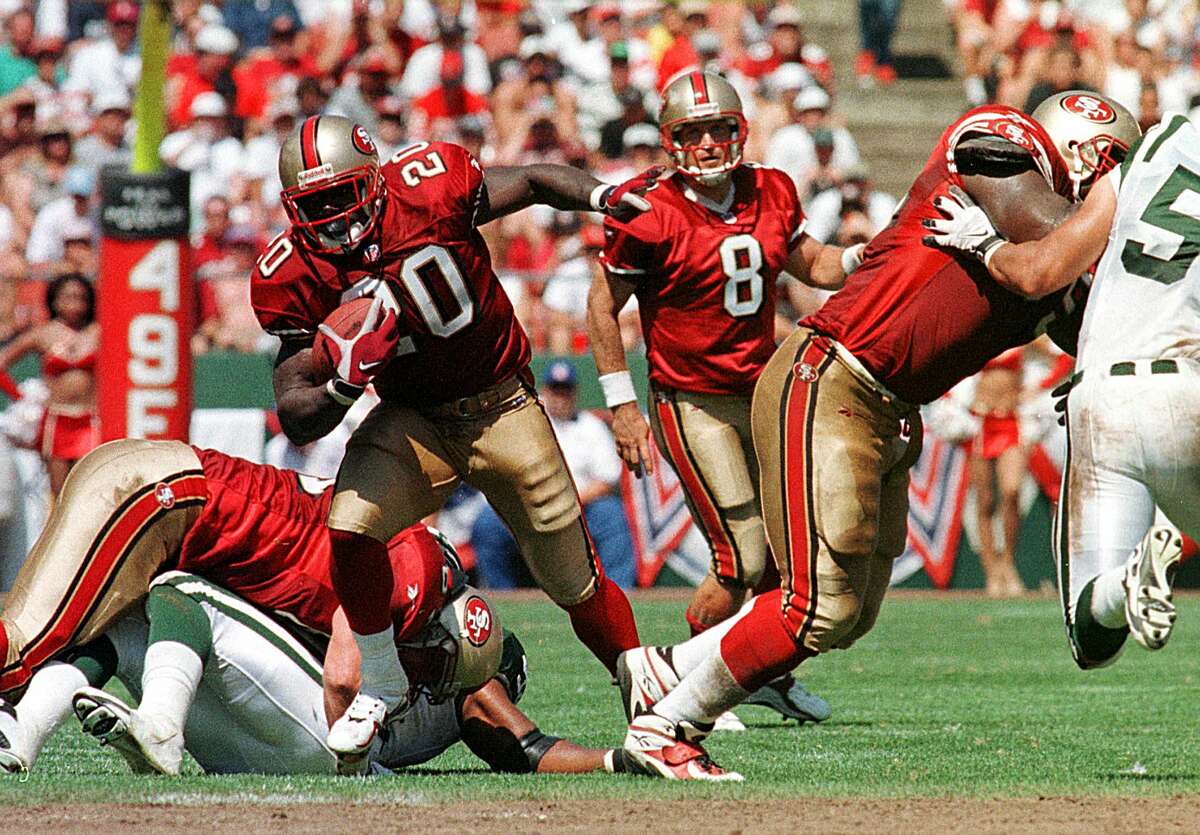 San Francisco 49ers running back Garrison Hearst (L) finds an opening after a hand-off from 49ers quarterback Steve Young (C) 06 September in San Francisco, CA. Hearst scored the winning touchdown in overtime to beat the Jets, 36-30. (Photo credit should read JOHN G. MABANGLO/AFP via Getty Images)