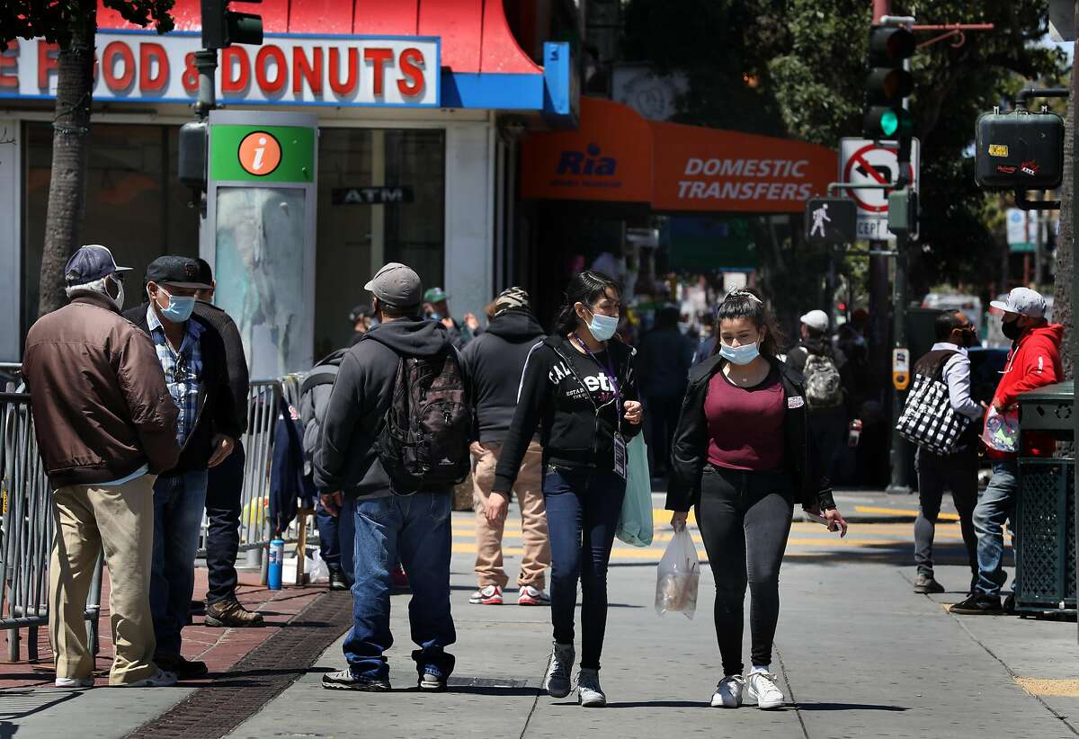 Pedestrians seen on Mission at 24th streets as businesses are re-opening in the Mission district on Tuesday, May 19, 2020, in San Francisco, Calif.