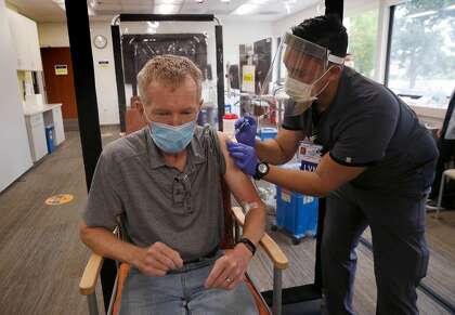 Damiel Amores administers a flu vaccine to Daniel Fitzpatrick at the Kaiser Permanente medical center in Redwood City.