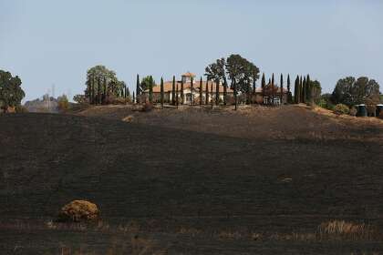 A structure still standing atop a charred hill with a burn line coming right up to it in Vacaville.
