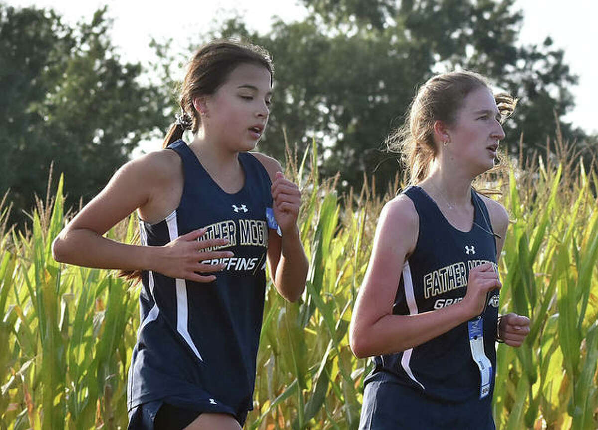 Father McGivney’s Kaitlyn Hatley, left, and Alyssa Terhaar work together through the second mile at the Mascoutah Invitational on Saturday.