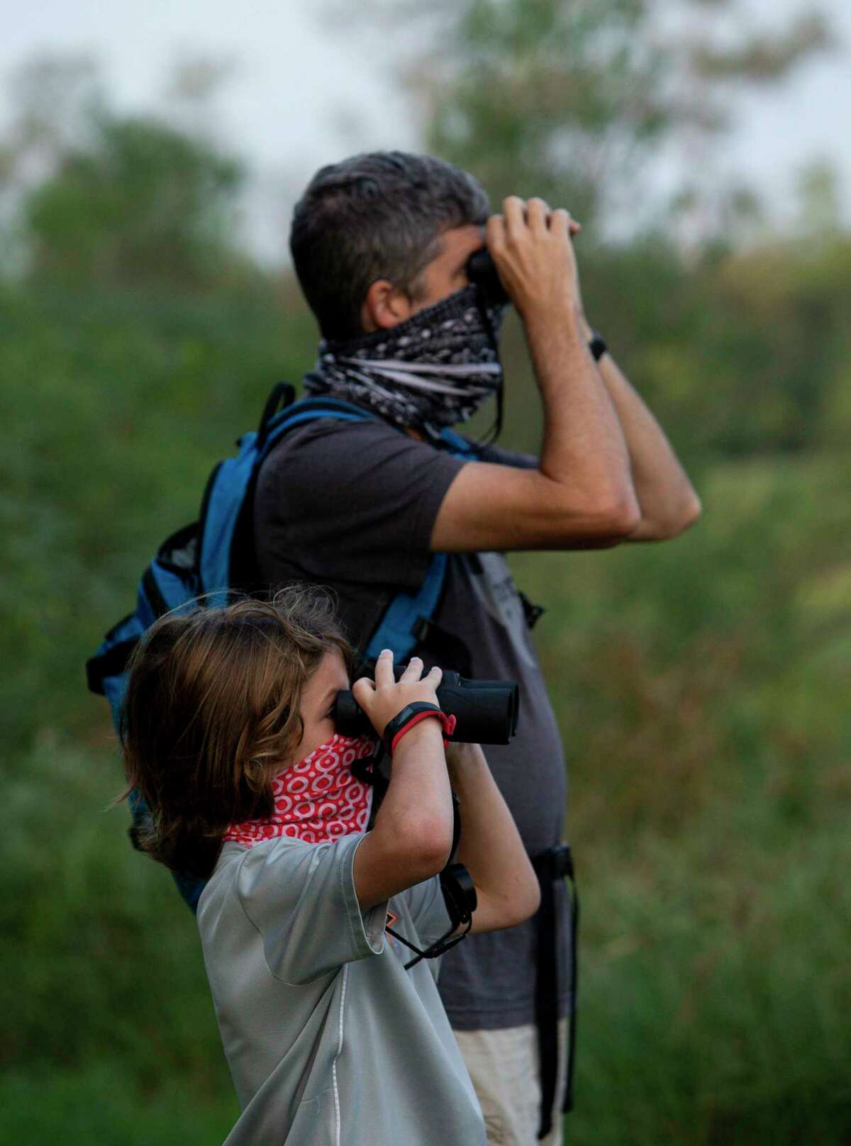 Miles Duboise, 10, and his father, John, use their binoculars to spot birds, during a bird walk at Spring Creek Nature Trails on Saturday, Sept. 19, 2020, in Tomball, Texas. The event kicked off Houston Bird Week.