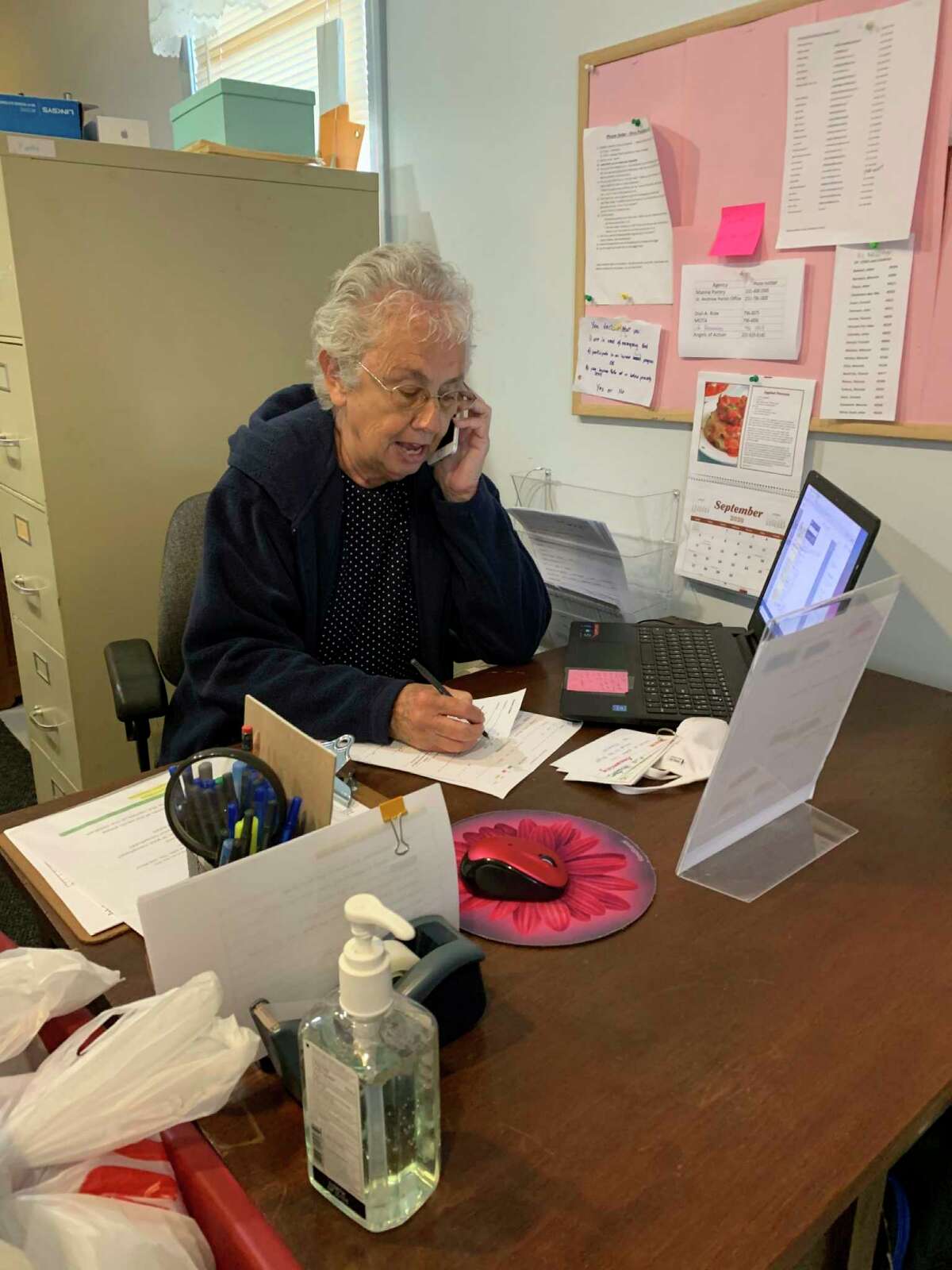 When not busy sorting bread, Sara Ham assists clients on the phone at Manna Pantry of Big Rapids, where she volunteers two days a week. (Submitted photo)
