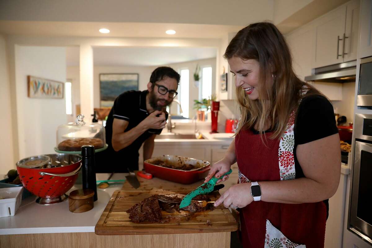 Gabi Moskowitz laughs as her husband Evan Wolkenstein takes a bite of her freshly baked BBQ brisket in their kitchen for Rosh Hashanah on Friday, September 18, 2020, in Novato, Calif. They are celebrating the holiday with family for a small dinner at home.
