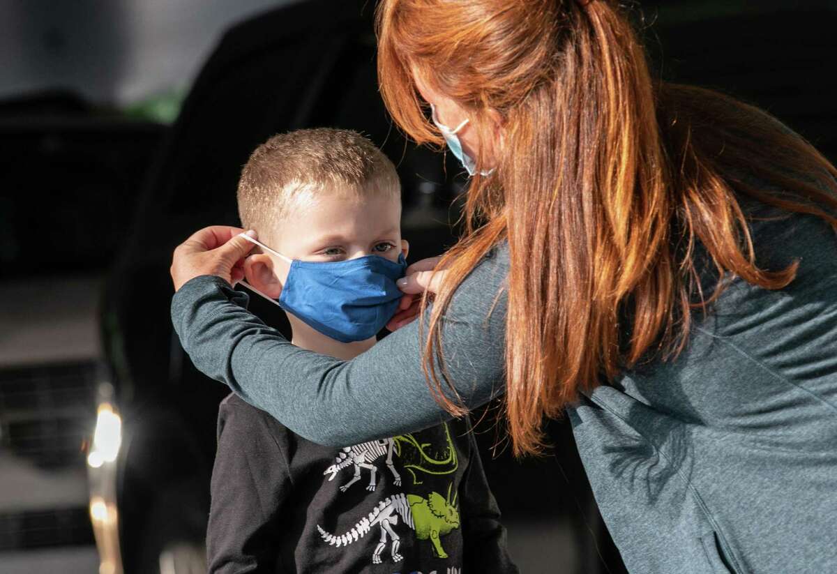A teacher puts on a child's mask upon his arrival at Stark Elementary School on September 16, 2020 in Stamford, Connecticut.