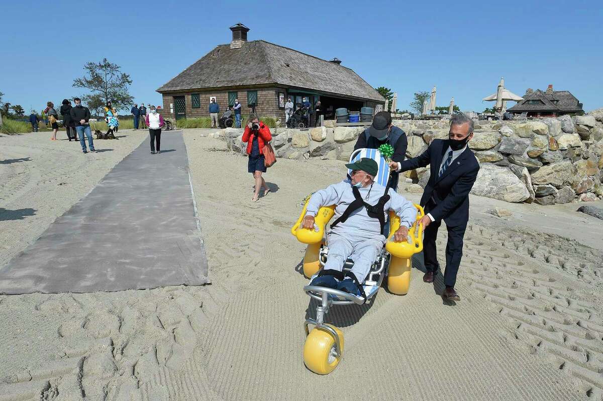 Greenwich First Selectman Fred Camillo and Lions Club member John O'Neill assist Joe Dowling of Old Greenwich as he tests out a Multi Function Beach Wheelchair capabilities on the sands of Greenwich Point in Greenwich, Connecticut on Sept. 21, 2020. The Greenwich Lions Club in coordination with the FSAC4PWD donated to the Town of Greenwich a new wheelchair for Tod's Point. This chair will allow people with limited mobility in town to enjoy the Long Island Sound.