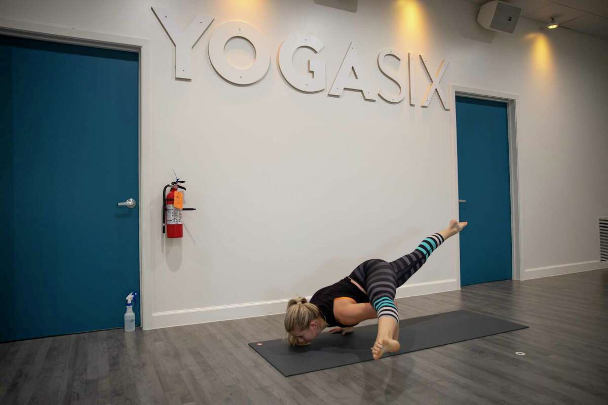 Lauren Walker demonstrates yoga techniques she uses when leading classes at YogaSix in The Woodlands, Thursday, Sept. 17, 2020. YogaSix adopted policies such as social distancing and mandatory masks when entering the facility to ensure the safety of their patrons and staff.