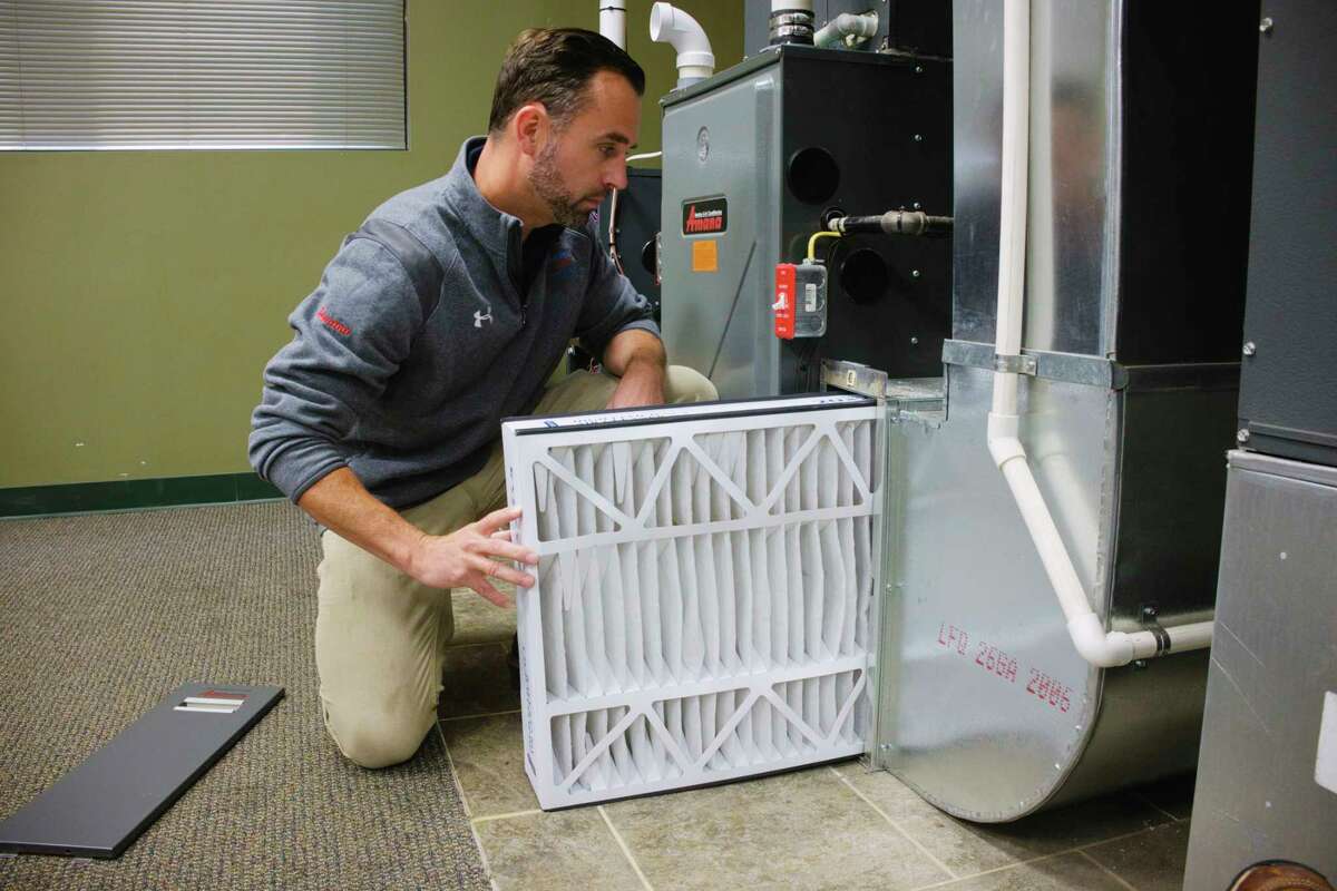 Jason Bethon, residential project manager at Albany Mechanical Services, slides a merv 8 filter back into the holder on the furnace at the company's showroom on Thursday, Sept. 17, 2020, in Green Island, N.Y. (Paul Buckowski/Times Union)