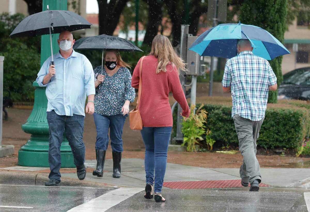Robert Cummings and his wife, Amy, make their way across West Davis Street as rainbands from Tropical Storm Beta make their way through Montgomery County, Tuesday, Sept. 22, 2020, in Conroe. The county is expected to receive additional rainfall from Beta through Wednesday.