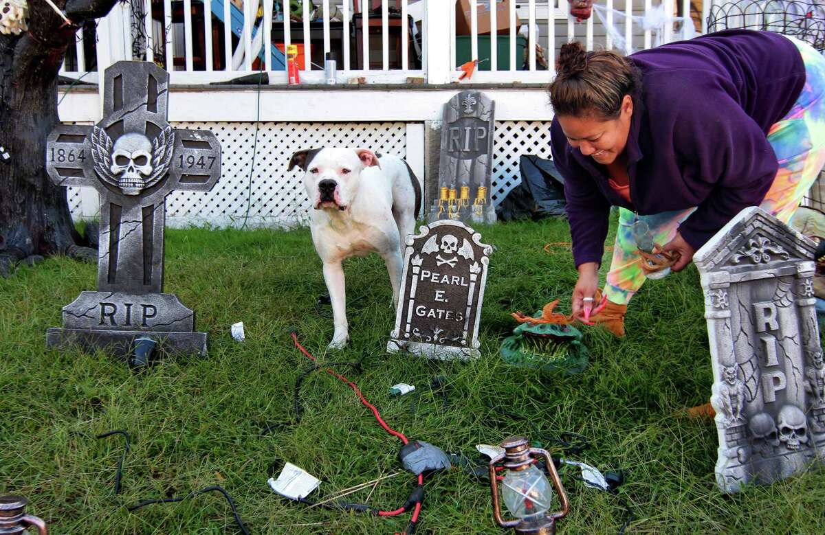 Chanel Owens sets up Halloween decorations in front of her home on Howard Avenue in Ansonia on Tuesday. Joining her in the yard is her dog Bishop.